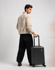 Small cabin suitcase, dark gray/black, with extended handle and four visible wheels