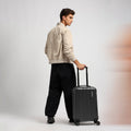 Small cabin suitcase, dark gray/black, with extended handle and four visible wheels