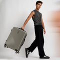 Hard-shell spinner suitcase, light silver-gray, carried on 8-wheel base with top handle