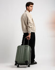 Small cabin suitcase with 8 wheels, dark green, carried by its handle at side