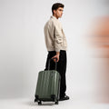 Small cabin suitcase with 8 wheels, dark green, carried by its handle at side