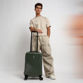 Dark green hard-shell carry-on suitcase with side handle and corner protectors.