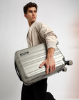 Small cabin suitcase with 8 wheels, silver-gray, held by the side handle