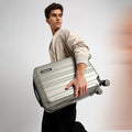 Small cabin suitcase with 8 wheels, silver-gray, held by the side handle