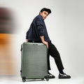 Dark green hard-shell check-in suitcase with telescopic handle and 8 spinner wheels, side view