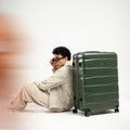 Large check-in suitcase, green hard shell being pulled on 4 spinner wheels