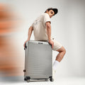 Light silver hard-shell check-in suitcase with telescopic handle and 8 spinner wheels, close side