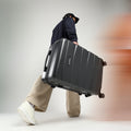 Large check-in suitcase, dark gray hard shell on 4 spinner wheels with side view