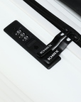 Black TSA-style lock and zipper track on white suitcase, close-up
