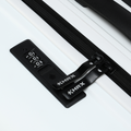 Black TSA-style combination lock and zipper pulls on a white suitcase, ribbed surface