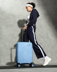 Small blue cabin suitcase with wheels, shown being pulled by a person