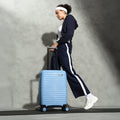Small blue cabin suitcase with wheels, shown being pulled by a person
