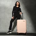 Peach hardshell check-in suitcase with upright handle and four-wheel base