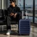 Blue cabin trolley standing with telescopic handle and four spinner wheels on the floor.