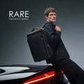 Black backpack worn by person, showing front panel and padded shoulder straps.