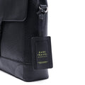 Black leather briefcase side view with front flap and hanging luggage tag