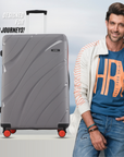 Grey hard-shell luggage with black top handle and red corner wheels, front view