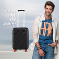Small cabin suitcase in black with telescopic handle and 8 wheels beside a traveler