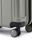 Small cabin suitcase close-up with silver-green shell, zipper edge, and 4 caster wheels.