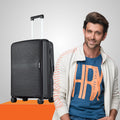 Medium polypropylene hard-shell suitcase, dark black, side view with handle and wheels
