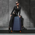 Blue rolling suitcase with ribbed texture and orange-accented wheels