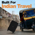 Black hard-shell suitcase with telescopic handle and 4 wheels, tilted on pavement.