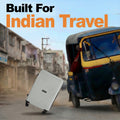 Light hard-shell suitcase with four wheels near a parked vehicle
