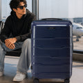 Large check-in trolley standing with telescopic handle and navy polypropylene shell.