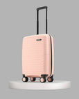 Peach small cabin suitcase on platform with telescopic handle and four wheels