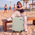 Medium check-in suitcase in light grey with ridged shell and 8 spinner wheels, beach scene