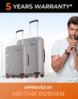 Two grey hard-shell suitcases with telescopic handles, red trim, and spinner wheels