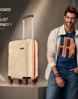 Beige cabin suitcase with telescopic handle, ridged front, and red-accent spinner wheels