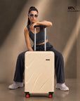 Beige cabin suitcase with trolley handle, front side panels, and four red-accent wheels