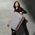 Grey medium check-in suitcase with telescopic handle and corner wheels, angled view