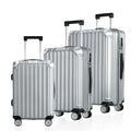 Three-piece polycarbonate suitcase set: three silver rolling suitcases standing side by side