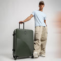 Small cabin suitcase in dark green with ribbed shell and telescopic handle on wheels