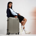 Large hard-shell check-in suitcase with 8 wheels and telescopic handle, dark silver.