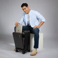 HRX Force Urban 2.0 trolley suitcase, black shell with orange trim, held by a person