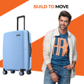 Hard-shell cabin suitcase, light blue with telescopic handle beside a standing man