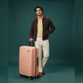 Peach medium check-in suitcase with ribbed shell and 8 spinner wheels, vertical side handle