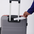 Grey hard-shell suitcase with telescopic handle and ID label on the front panel