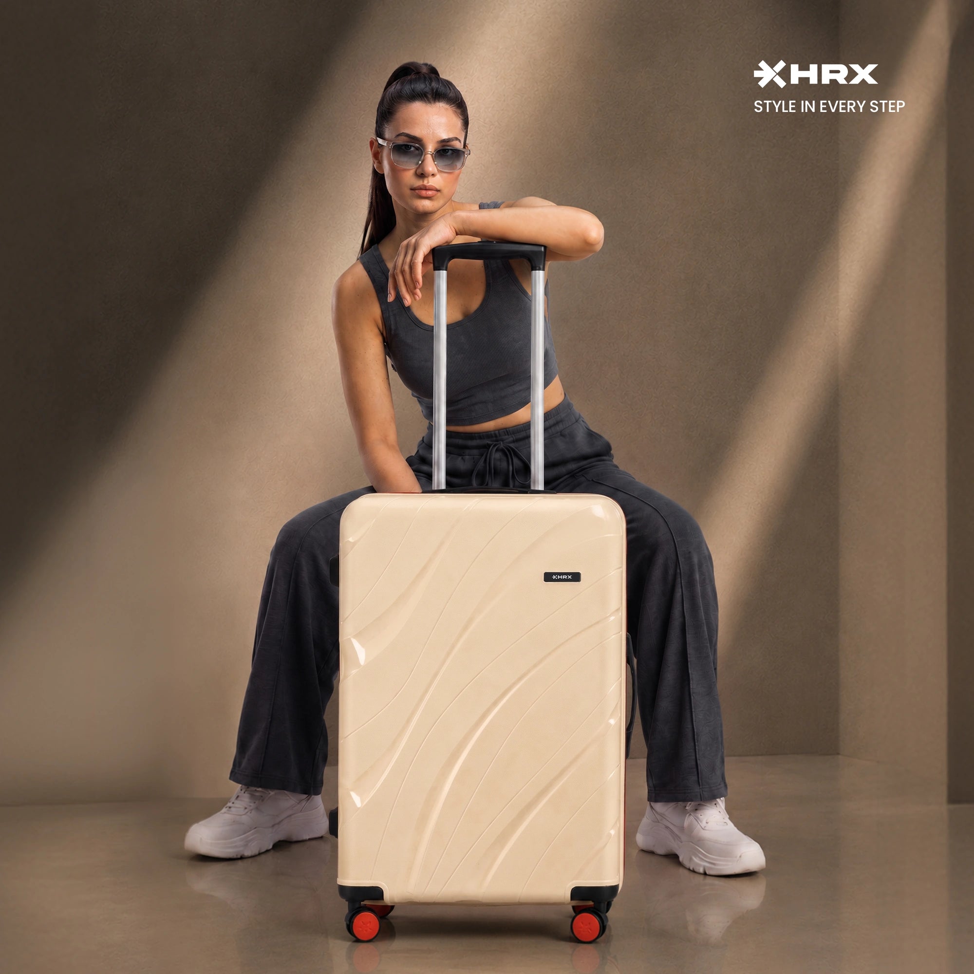 Beige cabin suitcase with telescopic handle, red-accent wheels, and side panel