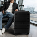 Large check-in trolley suitcase with telescopic handle in dark finish and four wheels