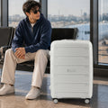 Light grey check-in trolley with ridged shell, telescopic handle, and low-profile spinner wheels.