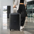 Black medium trolley with telescopic handle, pulled by person in an indoor lobby