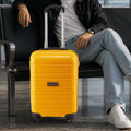 Yellow 4-wheel cabin trolley standing with telescopic handle and molded poly shell