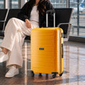 Yellow large check-in trolley with carry handle and four wheels beside a seated traveler