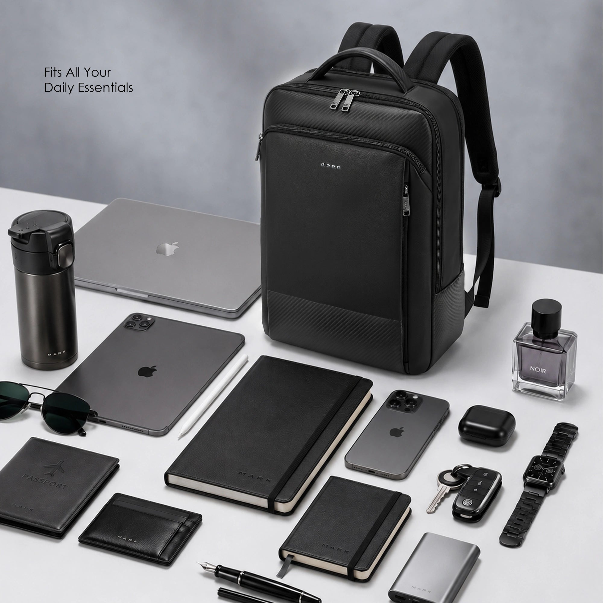 Black backpack with front tech pocket, displayed with laptop and small accessories.