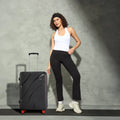 Black hard-shell check-in suitcase with telescopic handle and red wheels