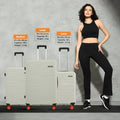Set of 3 hard-shell suitcases, light grey with orange wheels, beside standing model